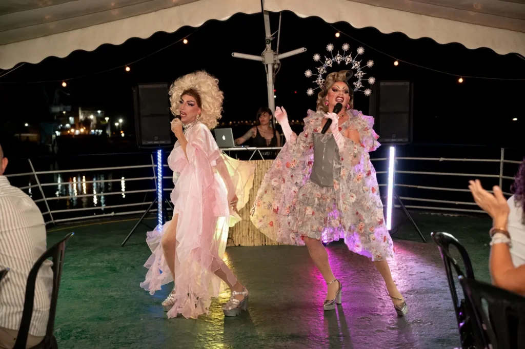 Las dos drag queens bailando y cantando en la pista del barco con el DJ a sus espaldas