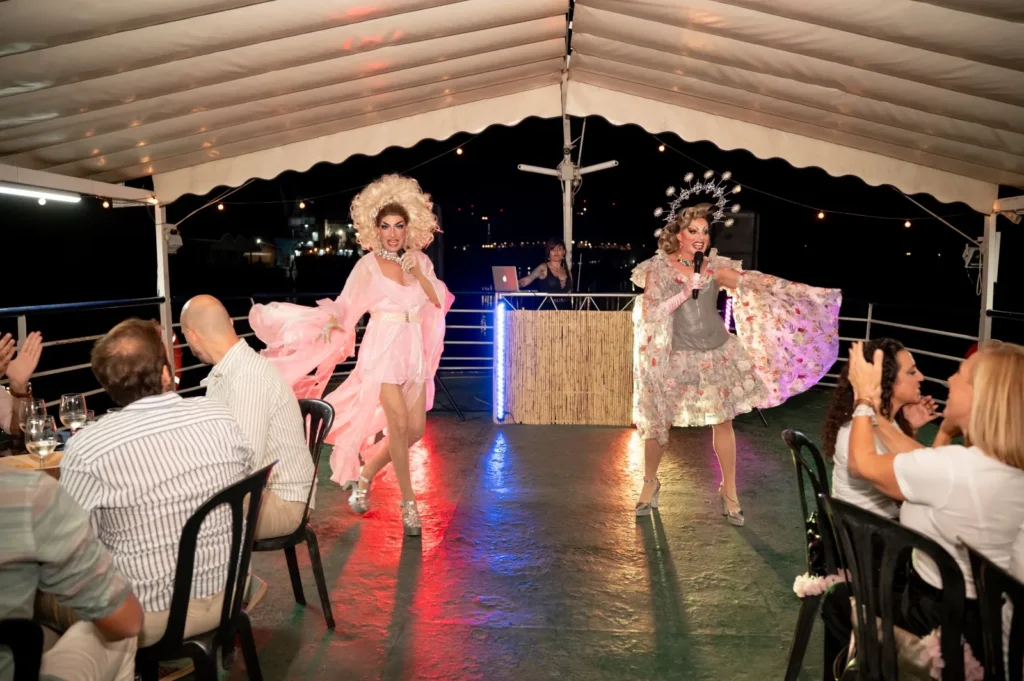 Espectáculo de drag queens en la cubierta del barco, con la cabina del DJ al fondo y los invitados en sus mesas
